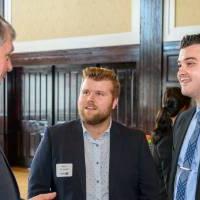 Two male alumni chat with President Haas